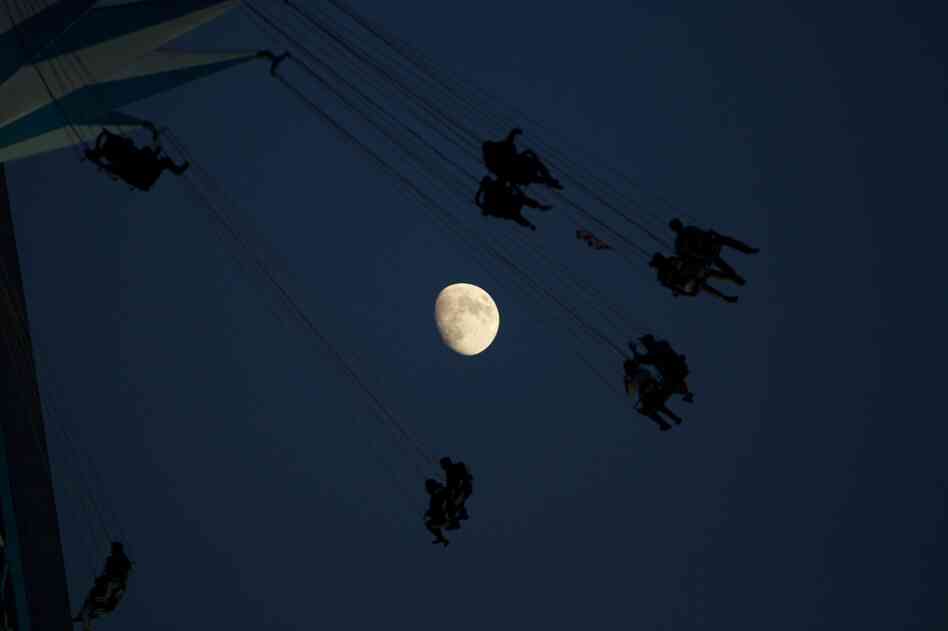 A waxing moon in the background of a fairground attraction in London on Sunday.
