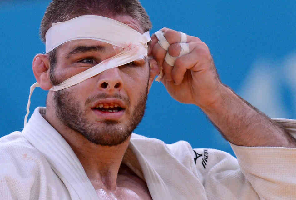 Travis Stevens adjusts his bandage as he competes with Germany's Ole Bischof during their men's -81kg judo contest semi-final match.