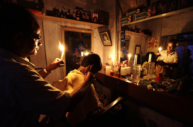 During the blackout on Tuesday, an Indian barber cut hair by candlelight in his shop in Kolkata.