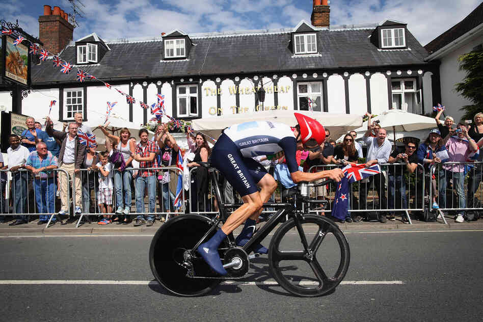 Bradley Wiggins of Great Britain cycles past a pub in Esher during the Men's Individual Time Trial Road Cycling.