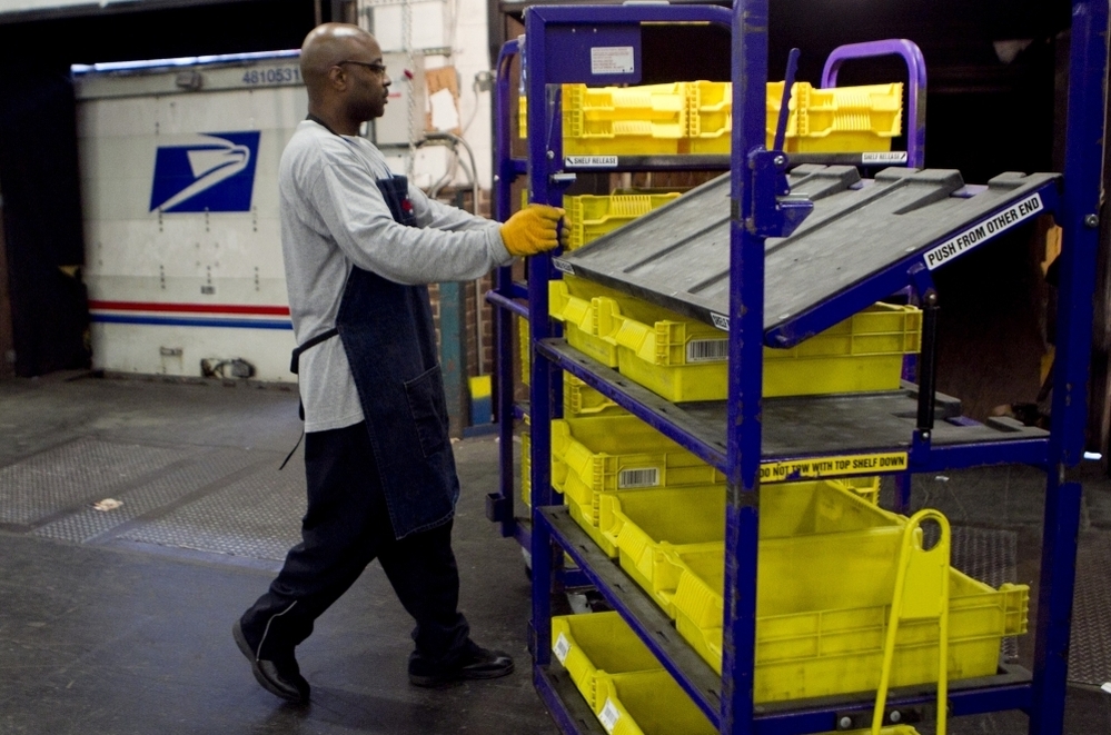 An employee loads flat trays onto a truck at the U.S. Postal Service processing and distribution center in Merrifield, Va.