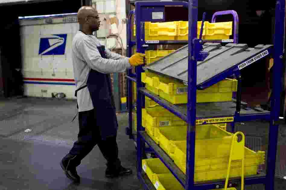 An employee loads flat trays onto a truck at the U.S. Postal Service processing and distribution center in Merrifield, Va.
