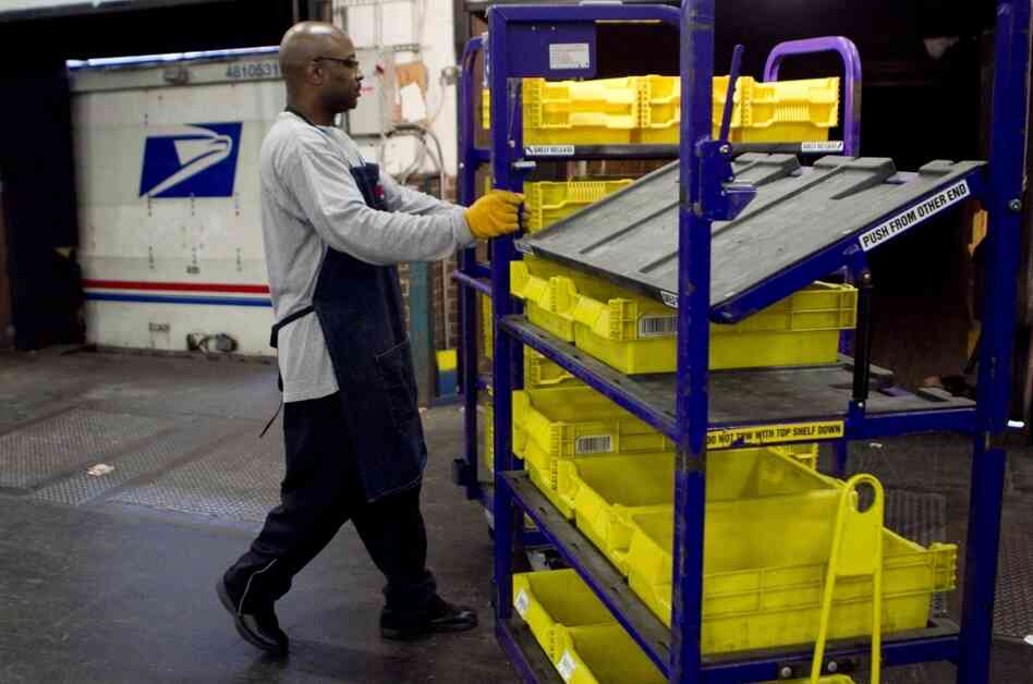 An employee loads flat trays onto a truck at the U.S. Postal Service processing and distribution center in Merrifield, Va.