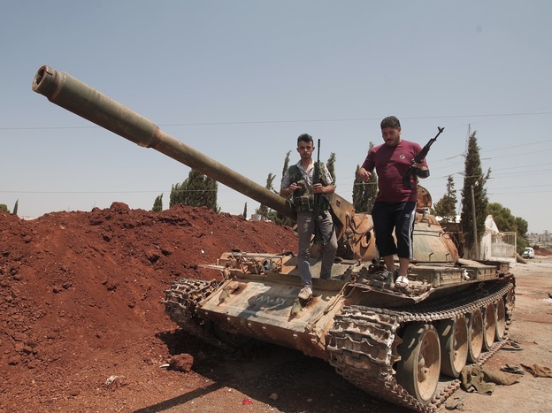Anti-Assad fighters stood atop a captured army tank on Wednesday in the village of Anadan, about 4 miles northwest of Aleppo.