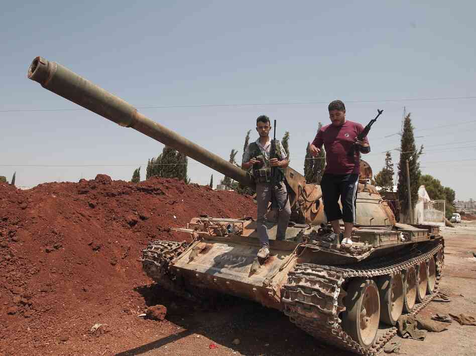 Anti-Assad fighters stood atop a captured army tank on Wednesday in the village of Anadan, about 4 miles northwest of Aleppo.