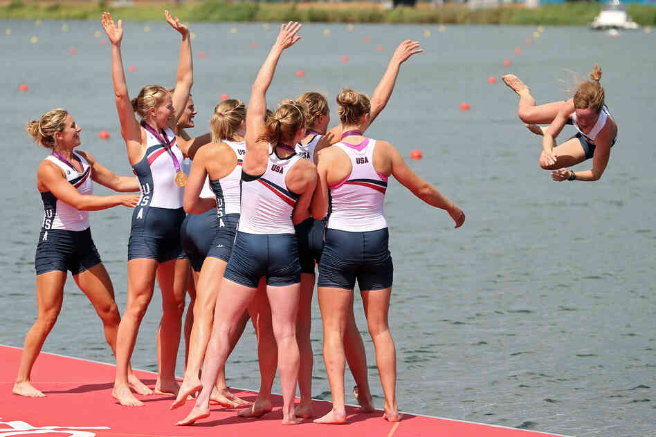 The U.S. rowing team throws their cox Mary Whipple into the water as they celebrate during the medal ceremony.
