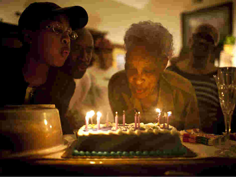 Ida Christian, who suffers from dementia, gets help from her granddaughter, Yolanda Hunter (left), in blowing out the candles on her birthday cake. Yolanda quit her lucrative job to become Ida's full-time caregiver.