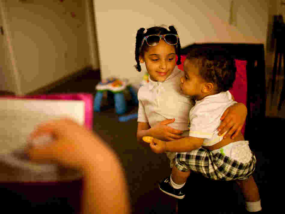 Shyanne (left) holds 1-year-old Makai, as Stepp checks to see if all of Shyanne's homework has been completed.