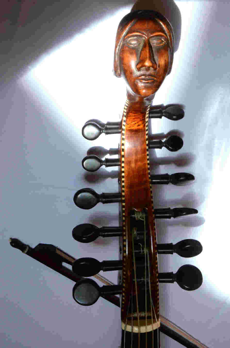 The carved head and peg box of an early 18th-century Baryton, a bass viol with additional metal strings that change the instrument's timbre. 