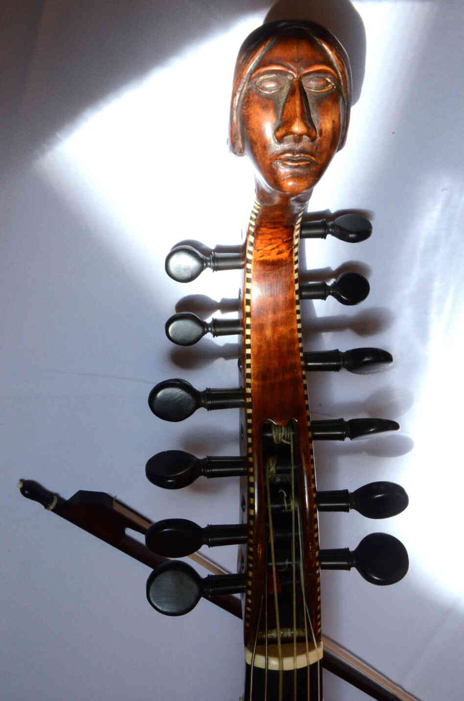 The carved head and peg box of an early 18th-century Baryton, a bass viol with additional metal strings that change the instrument's timbre. 