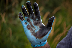 Bolenbaugh holds up a hand coated with oil sludge he has found in the Kalamazoo River two years after the spill, and two weeks after the state and EPA reopened the river to recreational use.