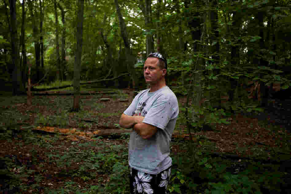 John Bolenbaugh stands in a forested stretch of the Kalamazoo River that borders a mobile home community in Battle Creek, Mich.