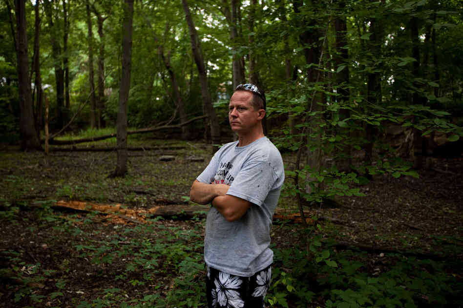 John Bolenbaugh stands in a forested stretch of the Kalamazoo River that borders a mobile home community in Battle Creek, Mich.
