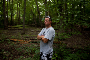 John Bolenbaugh stands in a forested stretch of the Kalamazoo River that borders a mobile home community in Battle Creek, Mich.