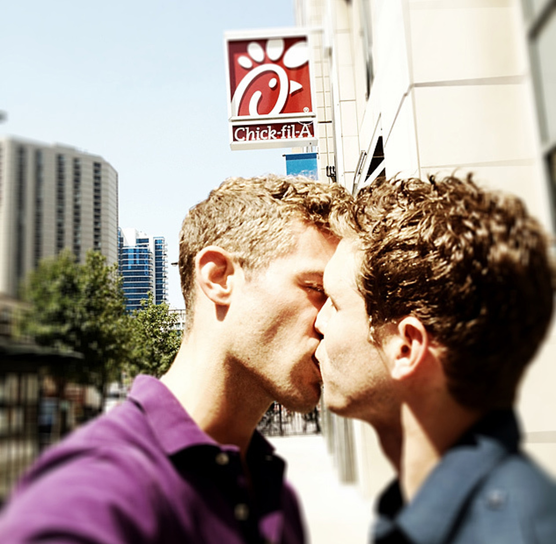 As part of a protest, two men kiss in front of a Chick-fil-A.