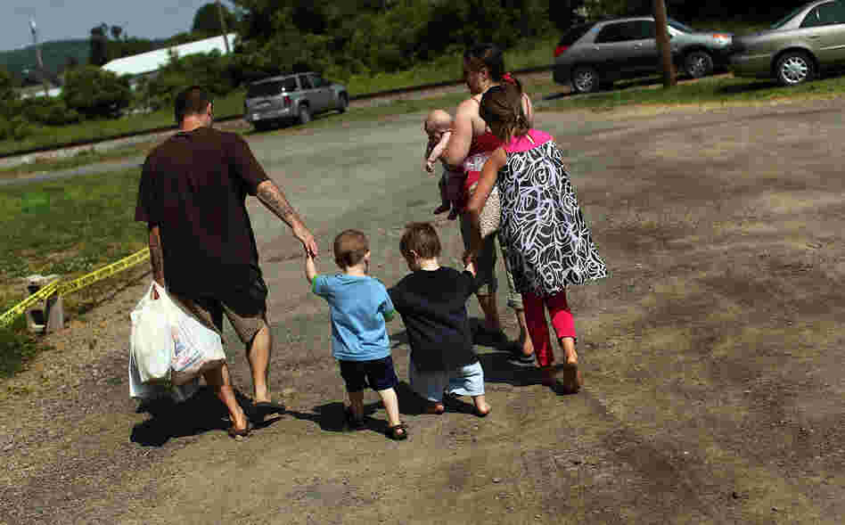 Members of the Dolan family walk home with bags of food from the Southern Tier Mobile Food Pantry in Oswego, N.Y., in June. Food banks across the nation are reporting giant spikes in demand.