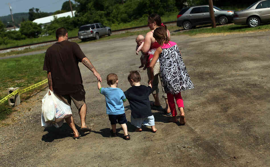 Members of the Dolan family walk home with bags of food from the Southern Tier Mobile Food Pantry in Oswego, N.Y., in June. Food banks across the nation are reporting giant spikes in demand.