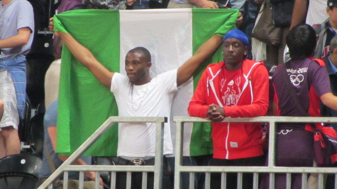 Nigerian fan Ifeoluwa Akande holds his country's flag as he watches Nigeria's basketball team lose to the United States by a record 83 points.