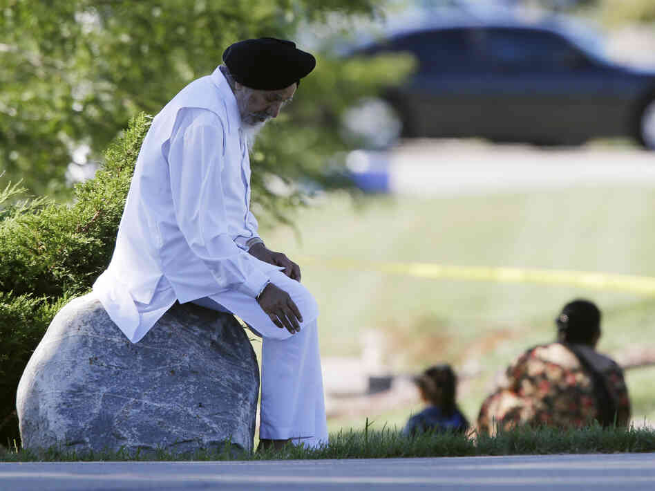 A man sits on a rock as police investigate.