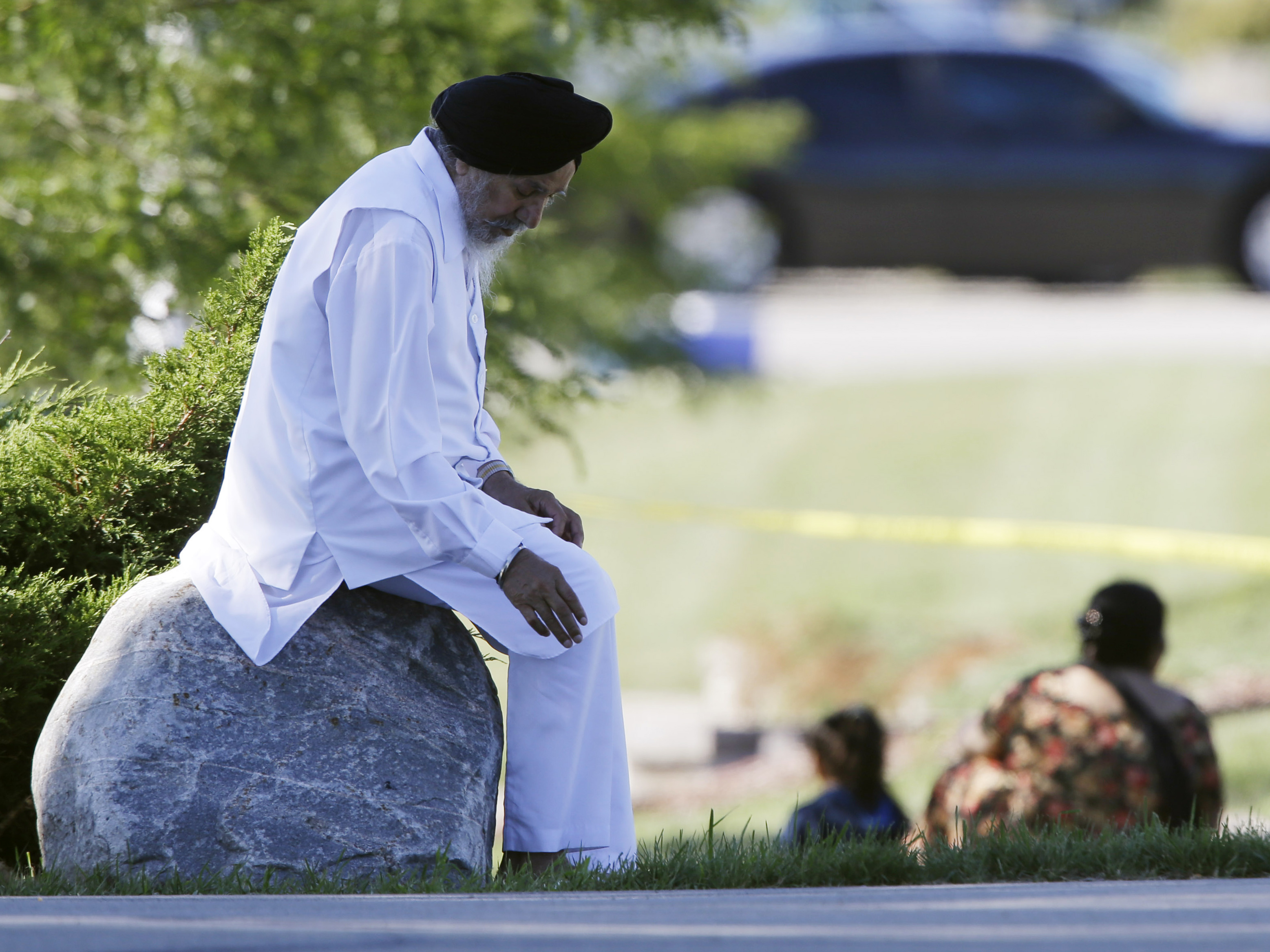 A man sits on a rock as police investigate.