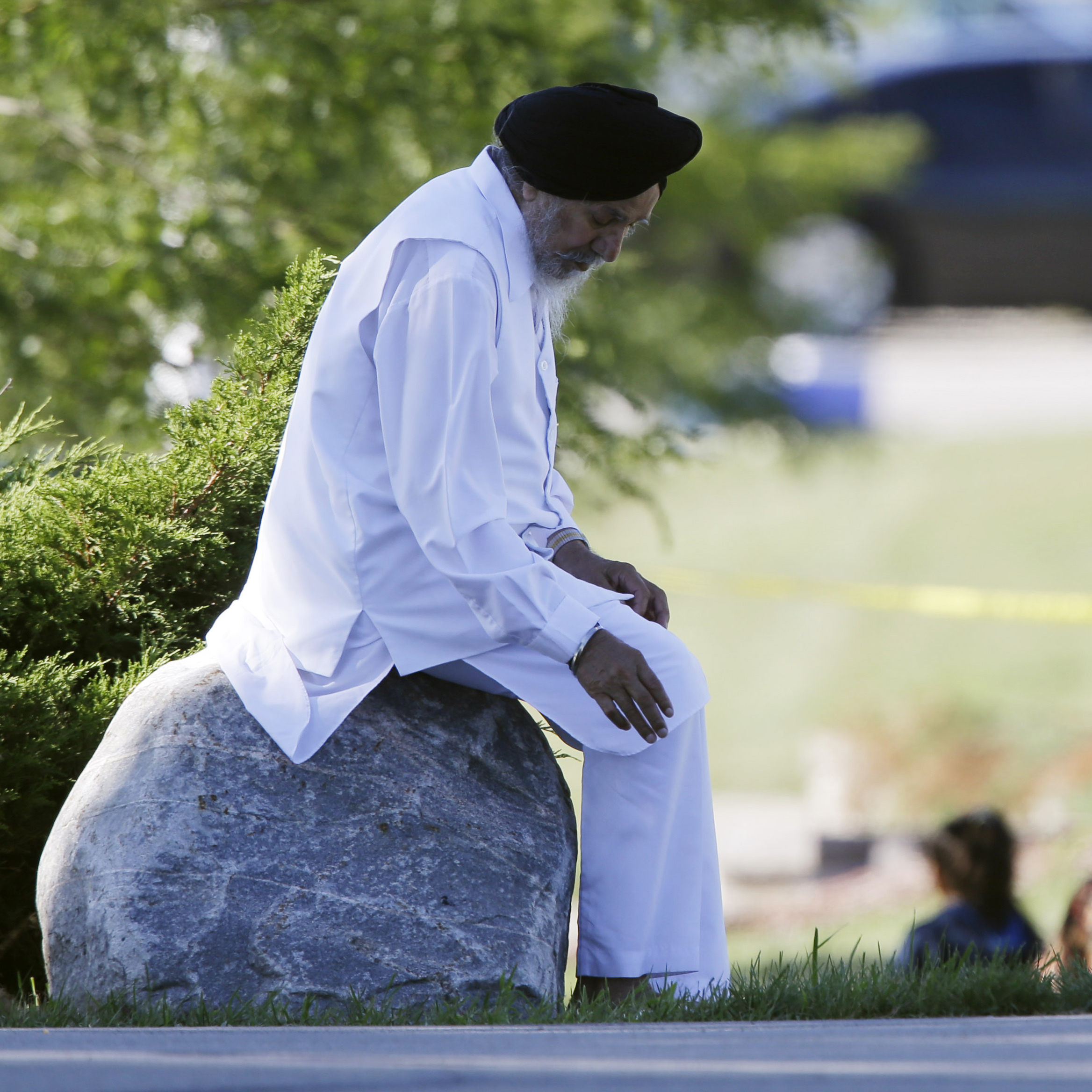 A man sits on a rock as police investigate.