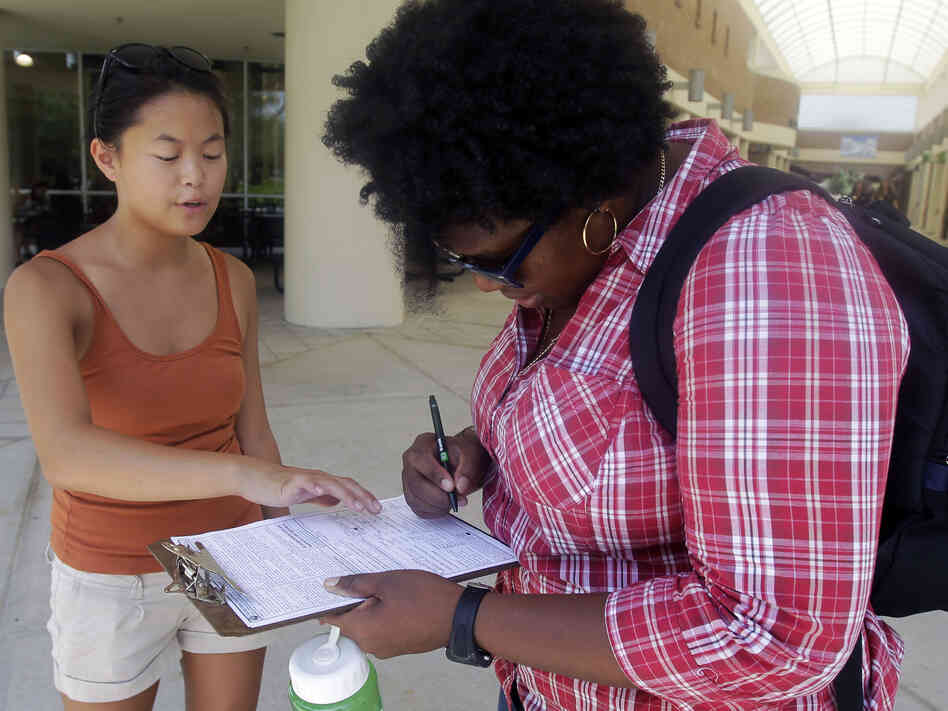 Aubrey Marks (left) helps a University of Central Florida student to register to vote in Orlando, Fla., on July 31.