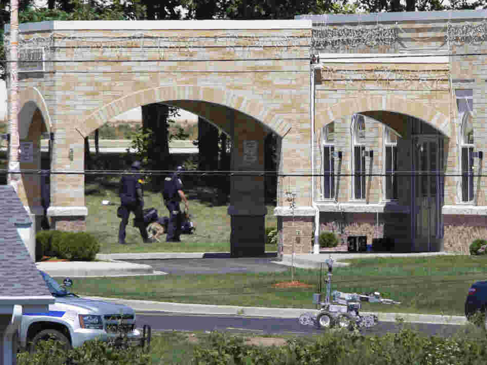 A police k-9 unit, left, and a robot, center, are outside the Sikh Temple.