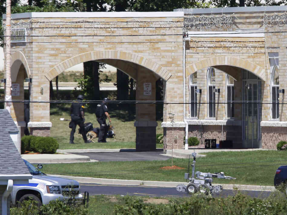 A police k-9 unit, left, and a robot, center, are outside the Sikh Temple.