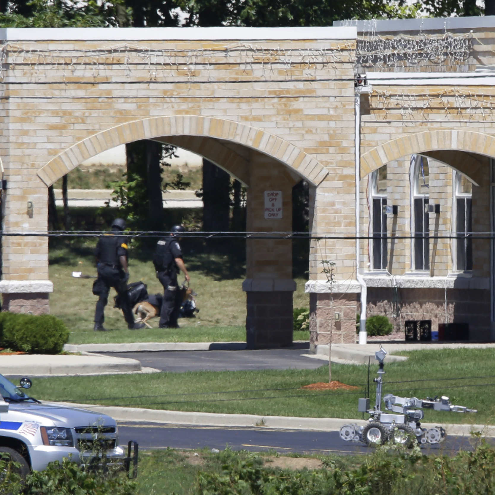A police k-9 unit, left, and a robot, center, are outside the Sikh Temple.