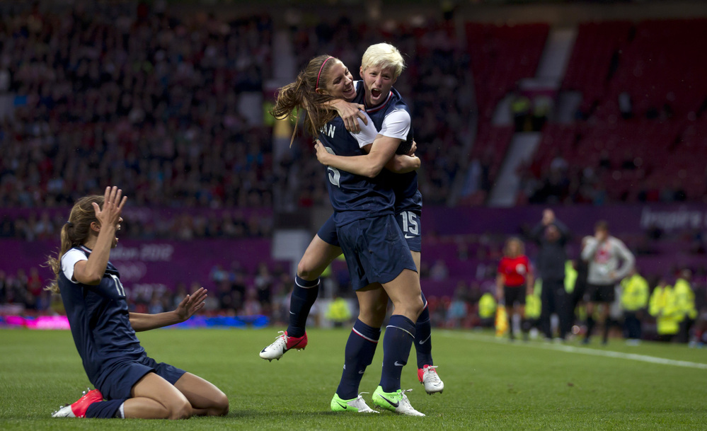United States' Megan Rapinoe, right, celebrates with teammate Alex Morgan as Tobin Heath slides in on her knees after scoring against Canada during their semifinal women's soccer match at the 2012 London Summer Olympics, Monday.