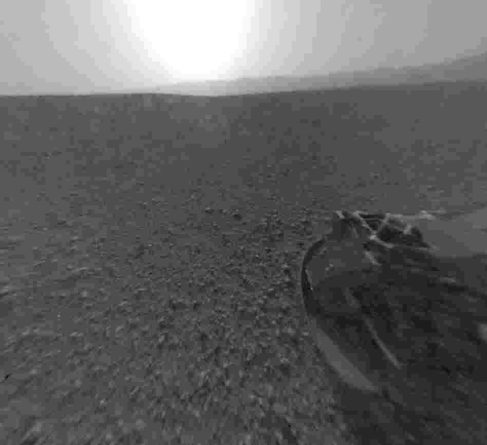 Part of the rim of Gale Crater, which is a feature the size of Connecticut and Rhode Island combined, stretches from the top middle to the top right of the image. One of the rover's wheels can be seen at bottom right. Part of the rim of Gale Crater, which is a feature the size of Connecticut and Rhode Island combined, stretches from the top middle to the top right of the image. One of the rover's wheels can be seen at bottom right.