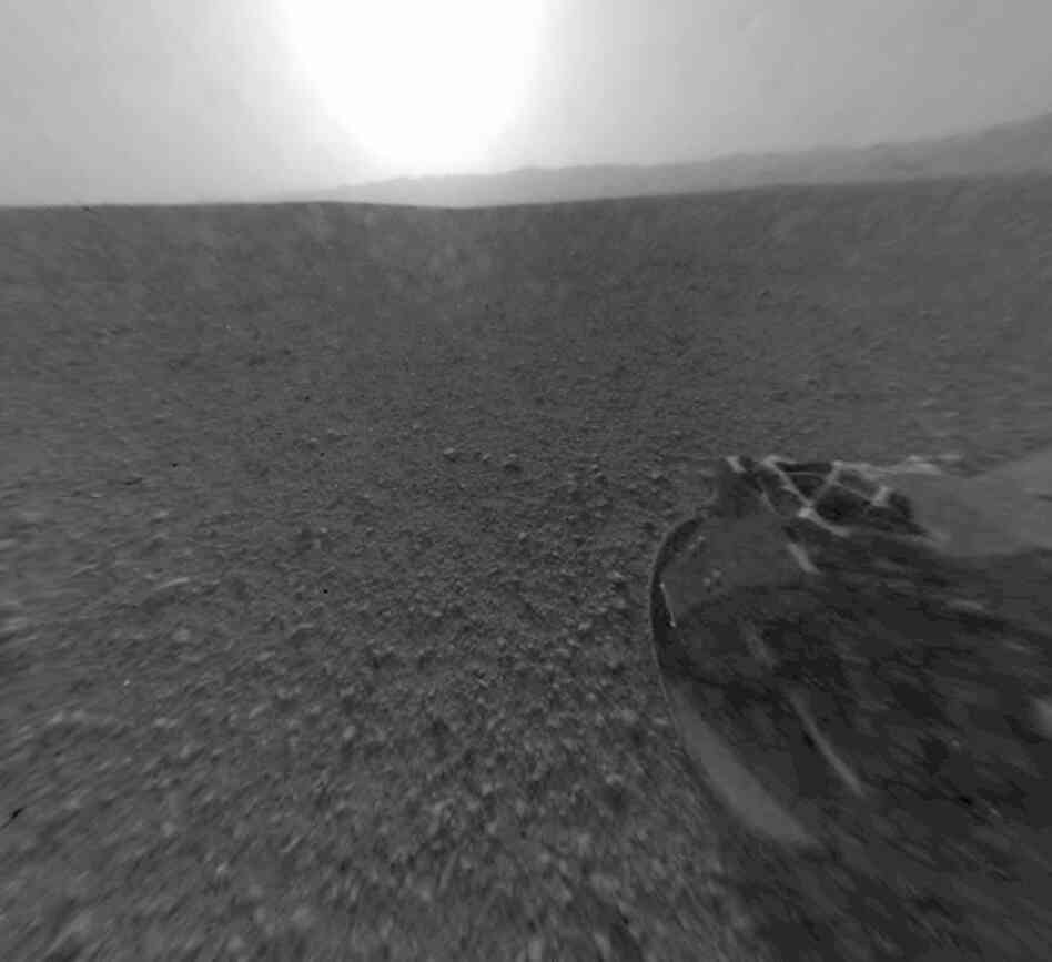 Part of the rim of Gale Crater, which is a feature the size of Connecticut and Rhode Island combined, stretches from the top middle to the top right of the image. One of the rover's wheels can be seen at bottom right. Part of the rim of Gale Crater, which is a feature the size of Connecticut and Rhode Island combined, stretches from the top middle to the top right of the image. One of the rover's wheels can be seen at bottom right.