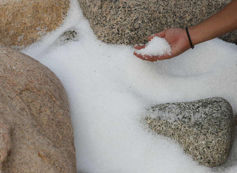 A volunteer collects plastic pellets washed up on a bank of Lamma island during a cleanup operation in Hong Kong on Sunday.