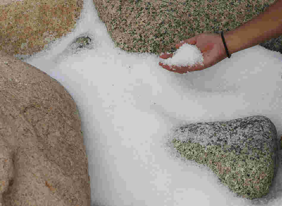 A volunteer collects plastic pellets washed up on a bank of Lamma island during a cleanup operation in Hong Kong on Sunday.