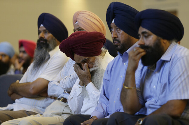 Members of the Sikh Temple of Wisconsin react at a news conference at Oak Creek Centennial church in Oak Creek, Wis. on Monday.