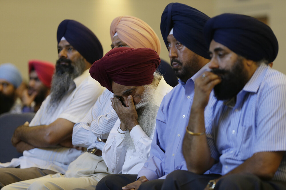 Members of the Sikh Temple of Wisconsin react at a news conference at Oak Creek Centennial church in Oak Creek, Wis. on Monday.