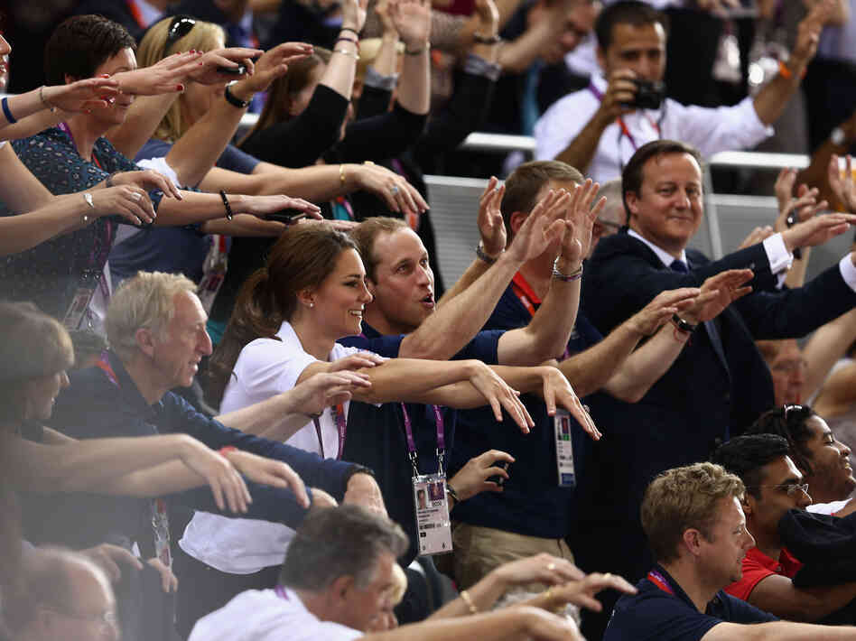 Prince William, his wife, Catherine, and Prime Minister David Cameron take part in the wave as they watch the track cycling at the London Games.
