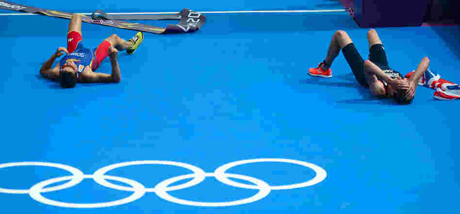 Triathlon gold medalist Alistair Brownlee of Britain (right) and silver medalist Javier Gomez of Spain lie on the ground after crossing the finish line in the London Games.