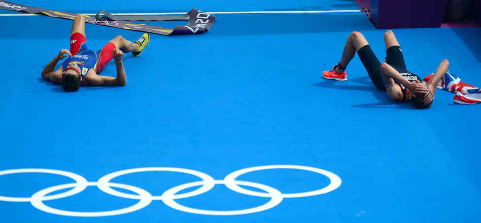 Triathlon gold medalist Alistair Brownlee of Britain (right) and silver medalist Javier Gomez of Spain lie on the ground after crossing the finish line in the London Games.