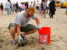 A volunteer picks up trash at a Nothin' But Sand beach cleanup. A volunteer picks up trash at a Nothin' But Sand beach cleanup.