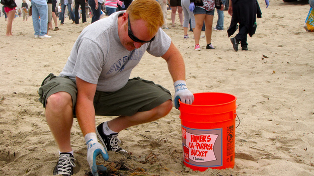 A volunteer picks up trash at a Nothin' But Sand beach cleanup.