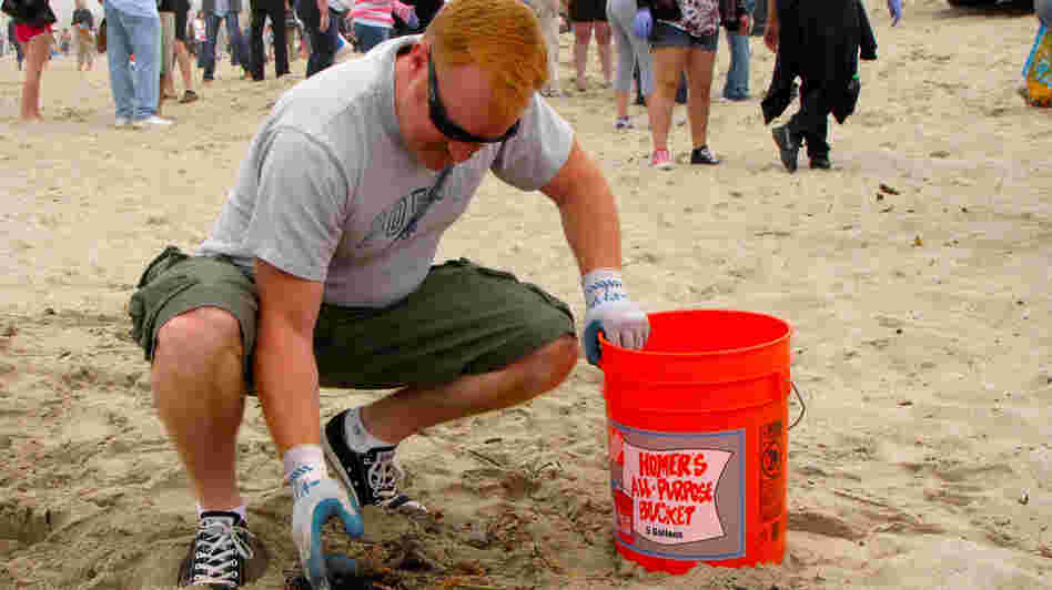 A volunteer picks up trash at a Nothin' But Sand beach cleanup.