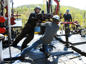 Workers move a section of well casing into place at a Chesapeake Energy natural gas well site near Burlington, Pa., in 2010.