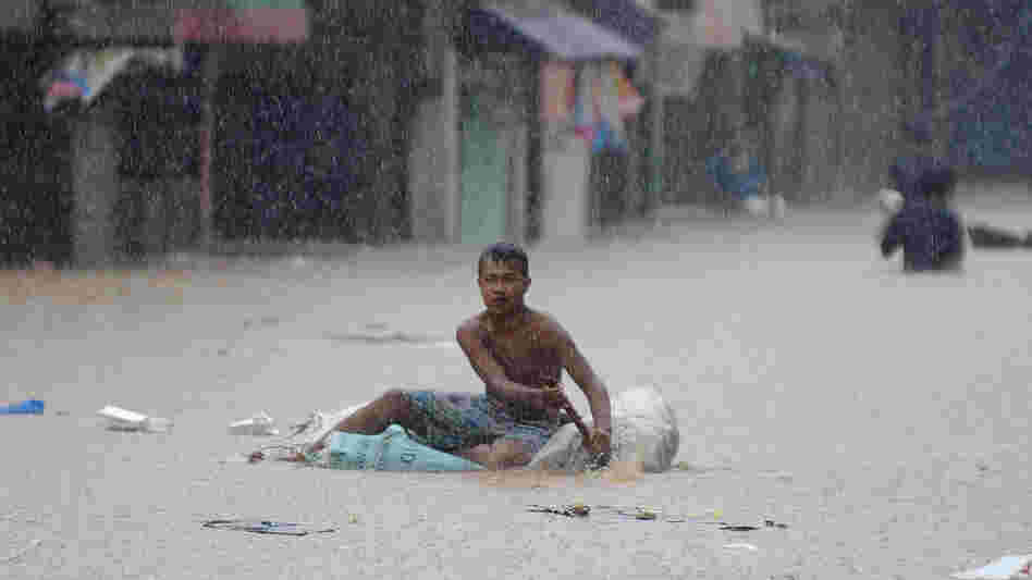 A man paddled an improvised raft along a flooded street in suburban Manila earlier today.