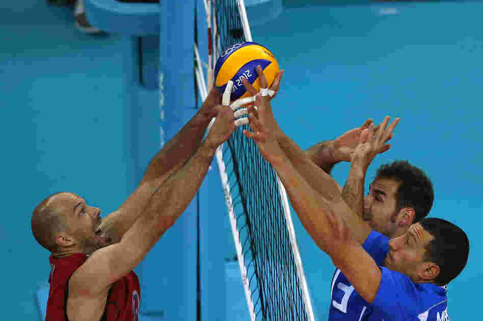 William Priddy (left) of the U.S. spikes the ball against Italy's Luigi Mastrangelo (right) and Dragan Travica during their men's quarterfinal volleyball match. Italy won the match 3-0.