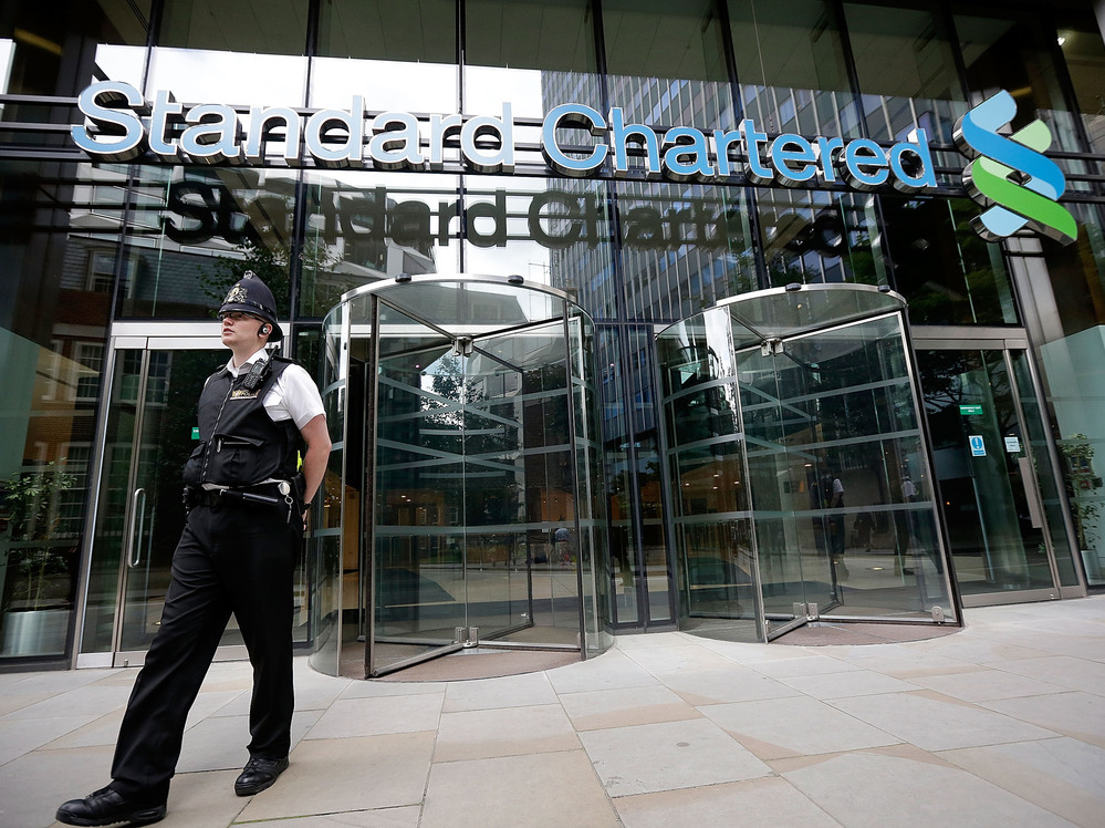 Police leave the Standard Chartered Bank's offices Tuesday in London. The bank has been accused of making billions of dollars' worth of transactions with the Iranian regime.