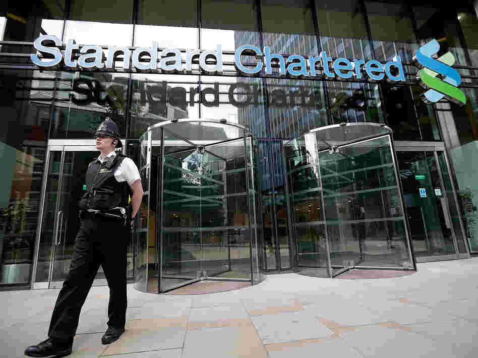 Police leave the Standard Chartered Bank's offices Tuesday in London. The bank has been accused of making billions of dollars' worth of transactions with the Iranian regime.