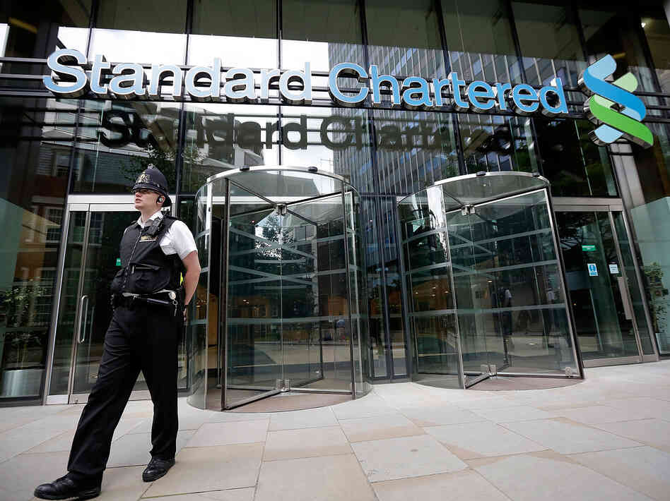 Police leave the Standard Chartered Bank's offices Tuesday in London. The bank has been accused of making billions of dollars' worth of transactions with the Iranian regime.