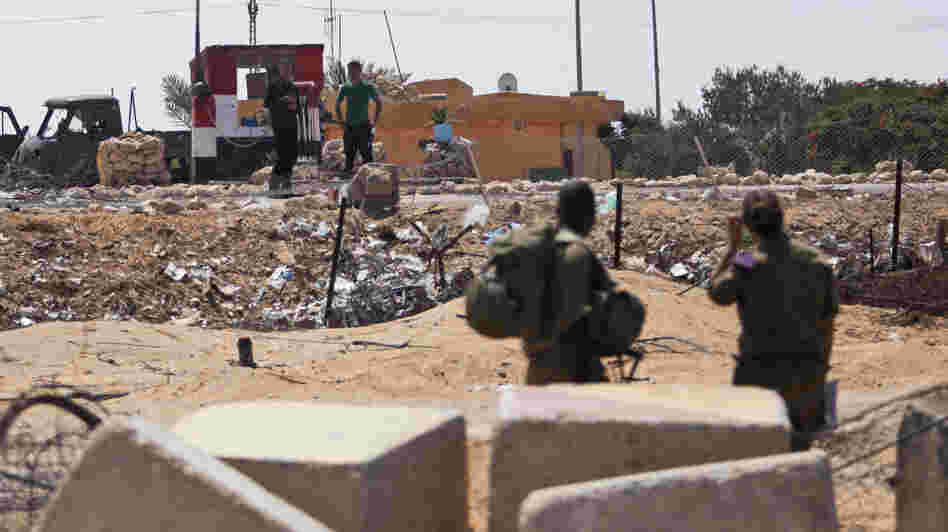 Israeli soldiers look at their Egyptian counterparts from their side of the border Wednesday at the Kerem Shalom border crossing, where an attack by Islamist militants on Sunday killed 16 Egyptian soldiers. Israeli soldiers look at their Egyptian counterparts from their side of the border Wednesday at the Kerem Shalom border crossing, where an attack by Islamist militants on Sunday killed 16 Egyptian soldiers.