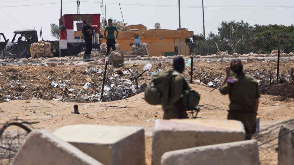 Israeli soldiers look at their Egyptian counterparts from their side of the border Wednesday at the Kerem Shalom border crossing, where an attack by Islamist militants on Sunday killed 16 Egyptian soldiers. Israeli soldiers look at their Egyptian counterparts from their side of the border Wednesday at the Kerem Shalom border crossing, where an attack by Islamist militants on Sunday killed 16 Egyptian soldiers.